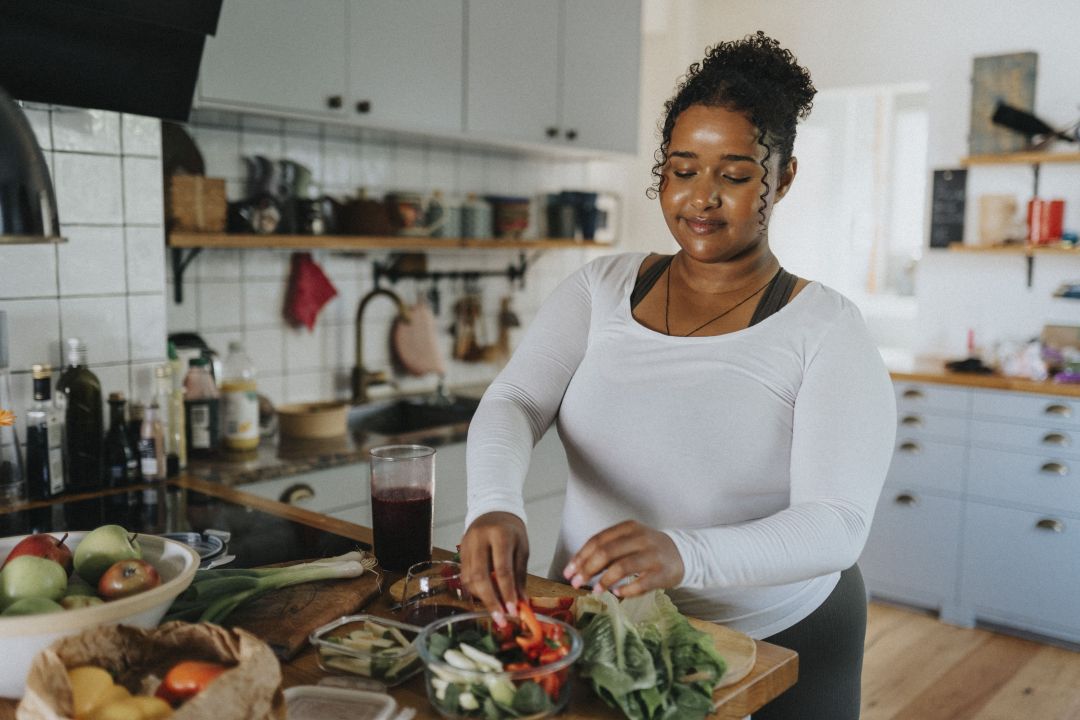 women in her kitchen cooking with vegetables