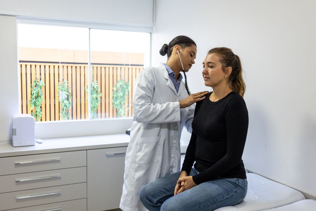 Provider listening to patient's heart in exam room