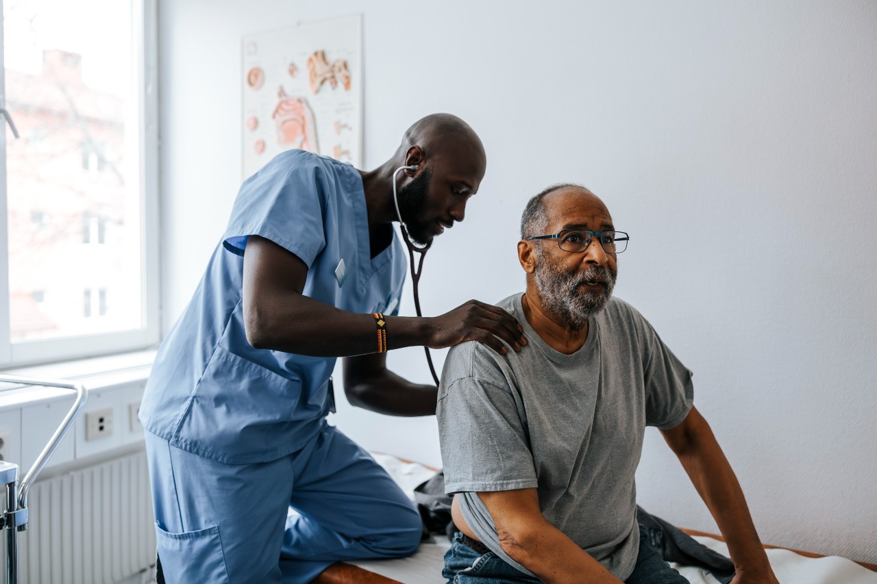 Doctor listening to a patients heart with a stethoscope in an exam room