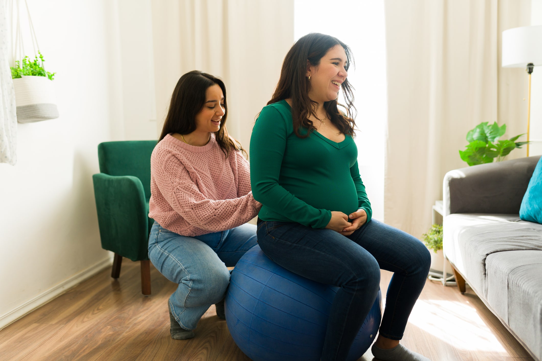 Female doula supporting pregnant woman on yoga ball