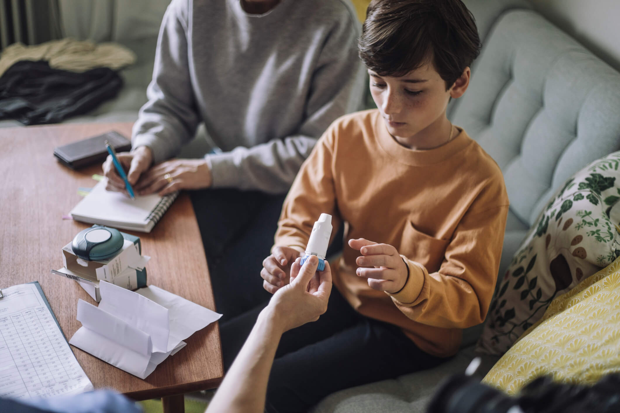 Young boy being handed an inhaler at an in-home doctors visit