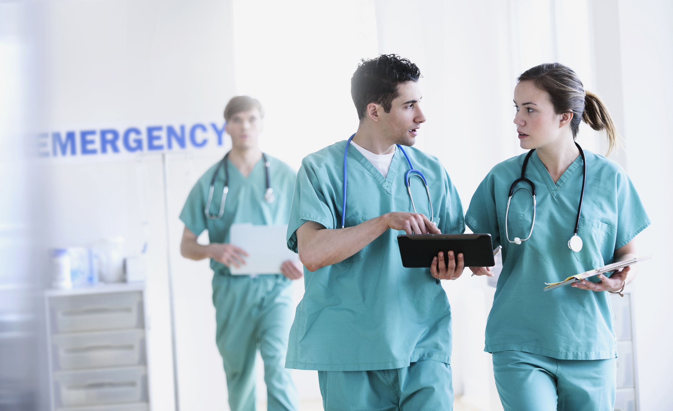 Three Medical Professionals Discussing as They Walk Away From the Emergency Center
