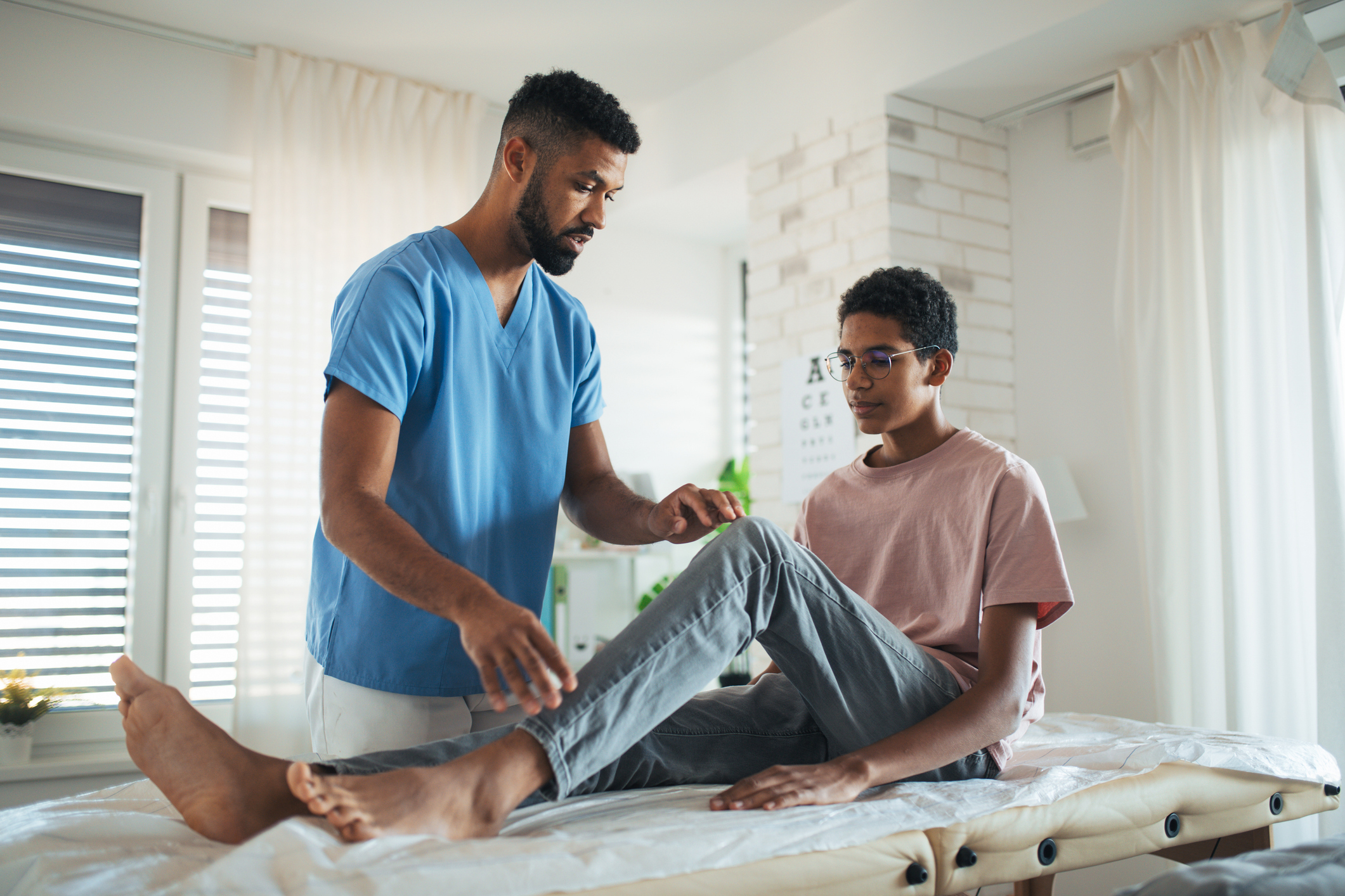 Male Physician Checking Young Males Reflexes in a Doctors Offices