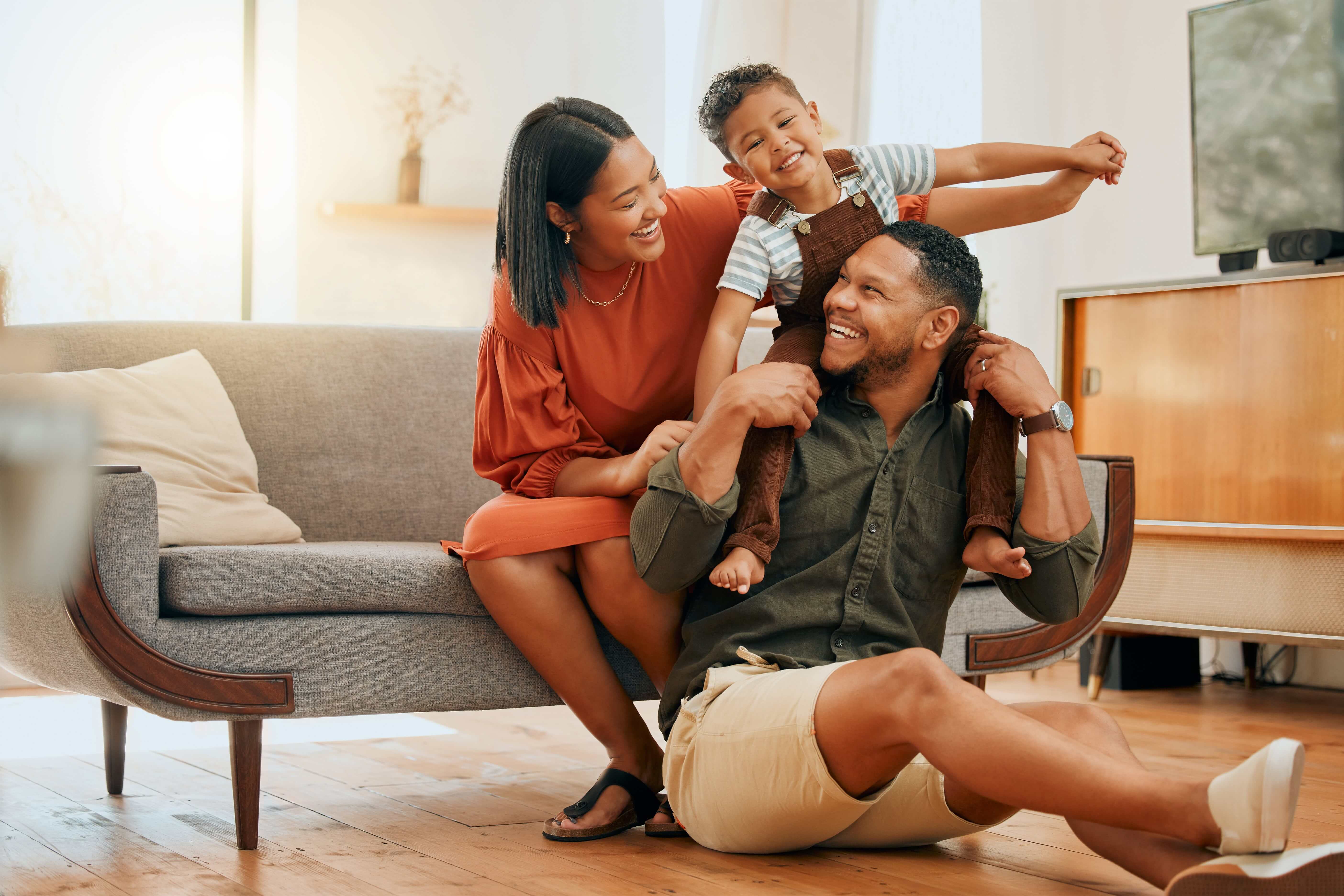 Family of three sitting on a couch, smiling at one another
