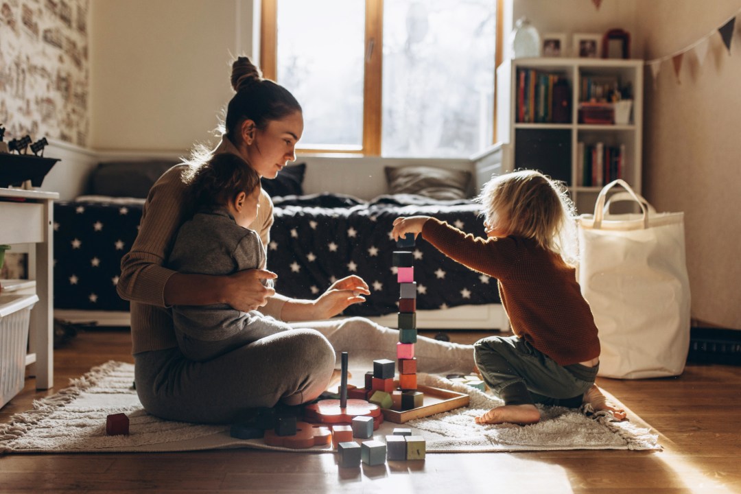 Mother playing blocks on the floor with two children