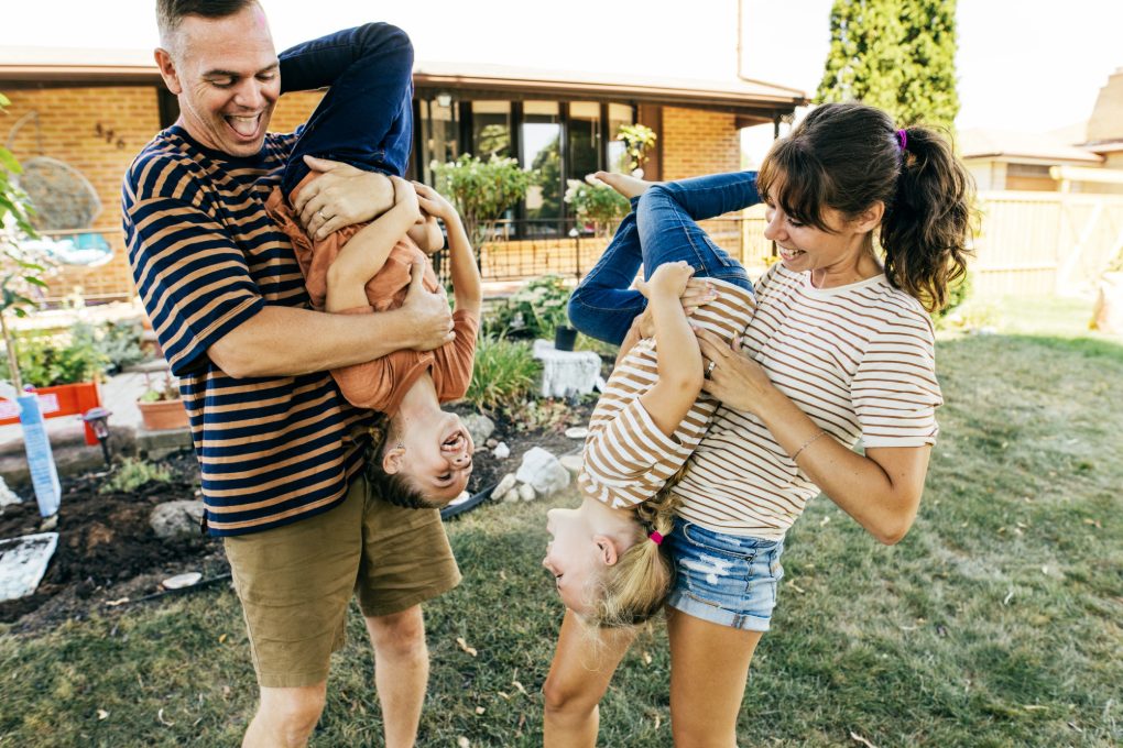 Family of four, parents holding their kids upside down