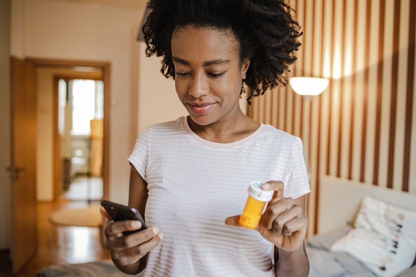 Women looking at device while holding pill bottle